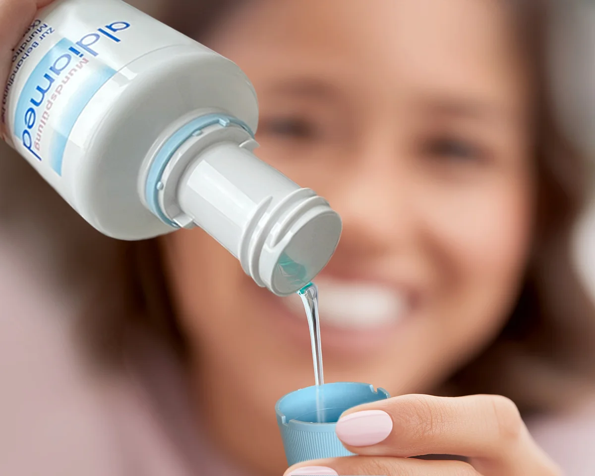 Eine Frau füllt die aldiamed Mundspülung in einen Anwendungsbecher um